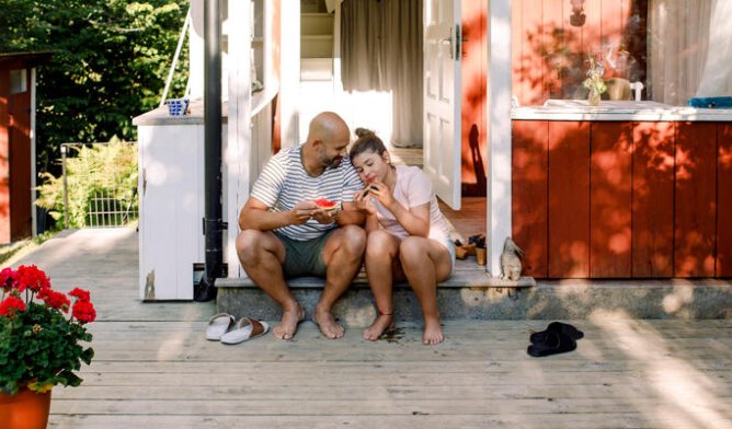 Far og datter utenfor rød hytte om sommeren.